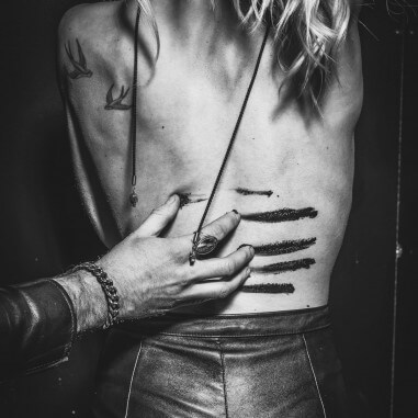 Photo d'une chevalière homme portée par un homme qui griffe sensuellement le dos d'une femme.