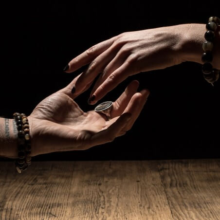 Photo de deux mains humùaines se rejoignant sur l'une d'elle est portée une chevalière homme en argent.