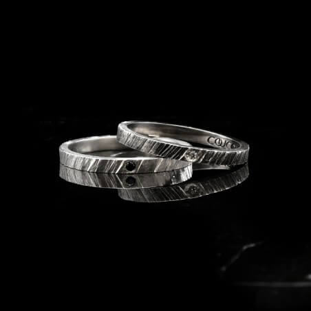 Photo de deux alliances fines diamant blanc modèle tungstène sur fond marbre noir.