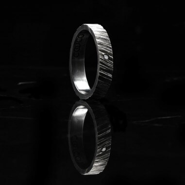 Photo de l'alliance homme avec diamant blanc modèle tungstène sur fond marbre noir vue de côté.