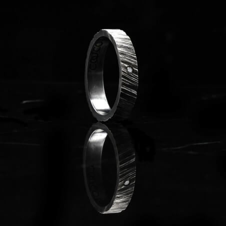Photo de l'alliance homme avec diamant blanc modèle tungstène sur fond marbre noir vue de côté.