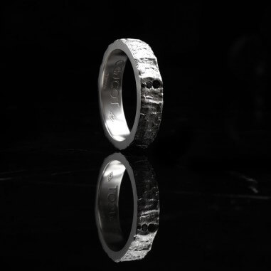 Photo sur un fond marbre noir et vue de côté de l'alliance homme avec diamant modèle Hyperion.