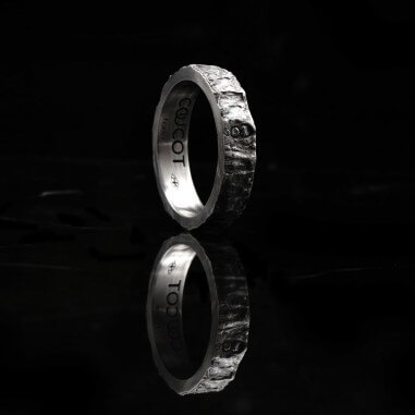 Photo de la bague alliance homme avec diamant blanc vue de côté sur fond marbre noir.