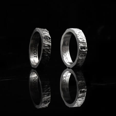 Photo de deux alliances pour homme avec diamant blancs côté à côte sur fond marbre noir.