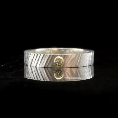 Photo sur fond marbre noir de l’alliance bicolore avec diamant modèle Tungstène.