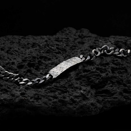 Photo sur fond lave noire de la gourmette homme en argent modèle Hypérion avec détail de la texture.