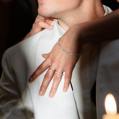 Photo d’une main de femme qui enlace un homme et qui porte à l’annulaire l’alliance originale en argent modèle A76 M.